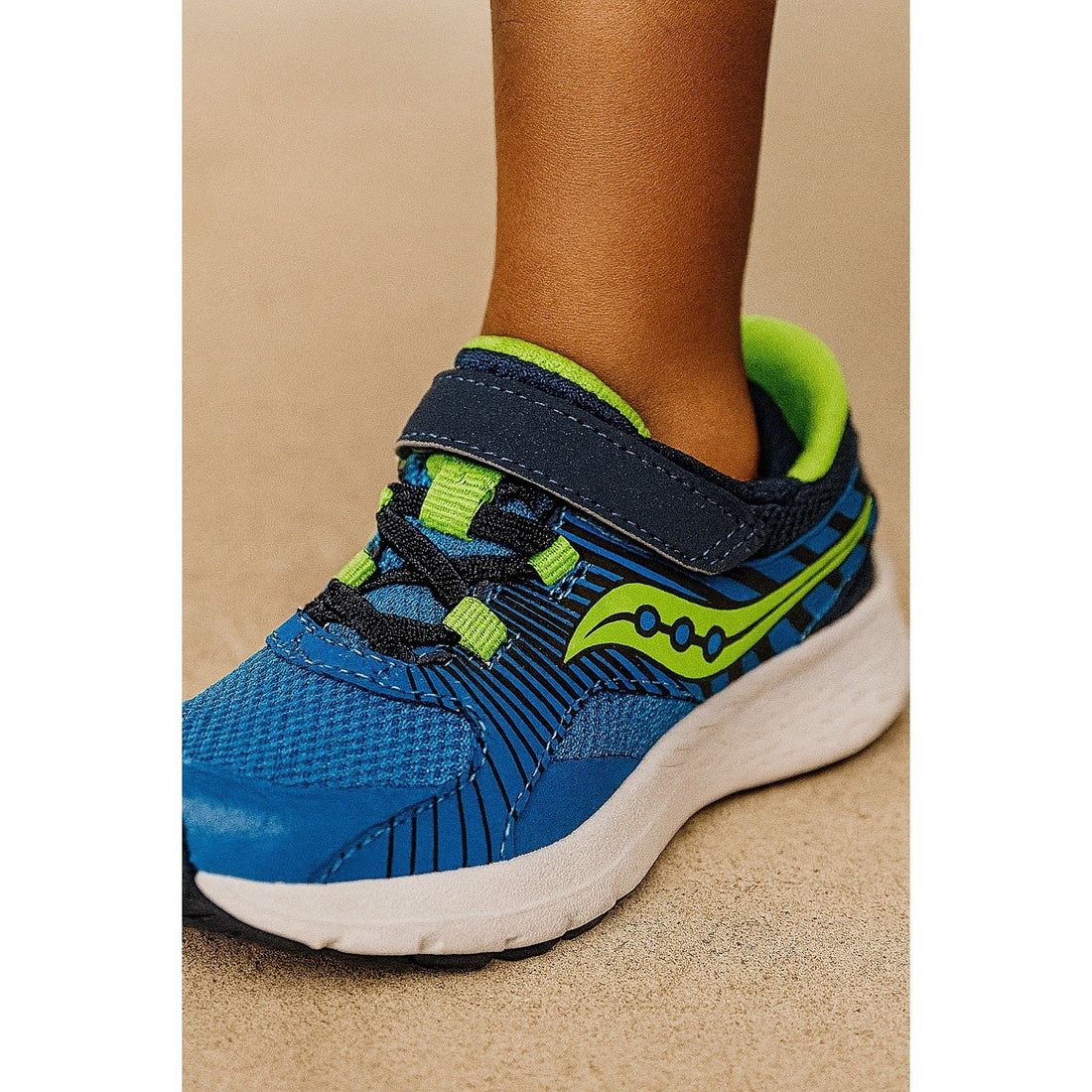 Blue and green sneaker with a visible brand logo on a beige background