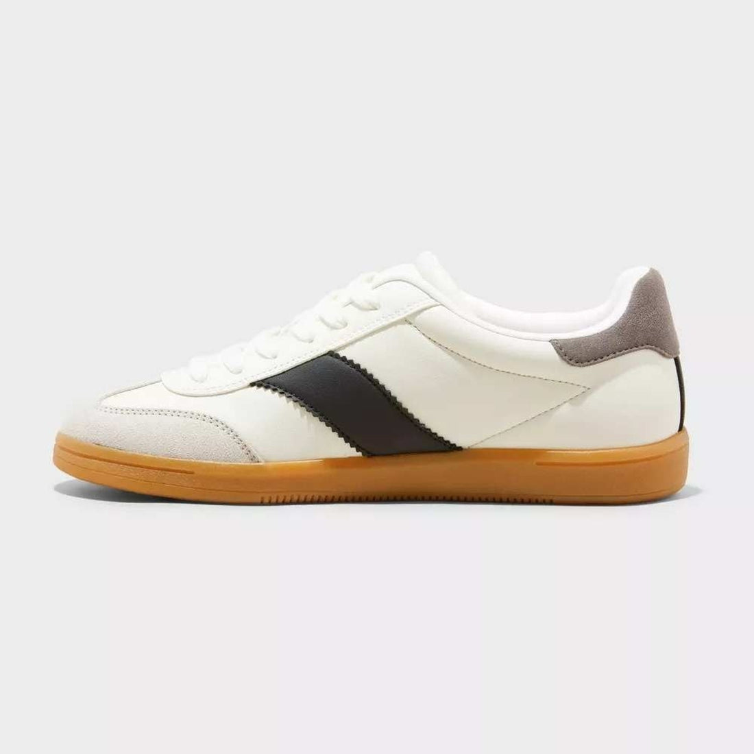 White sneaker with black accent and brown sole on a light gray background