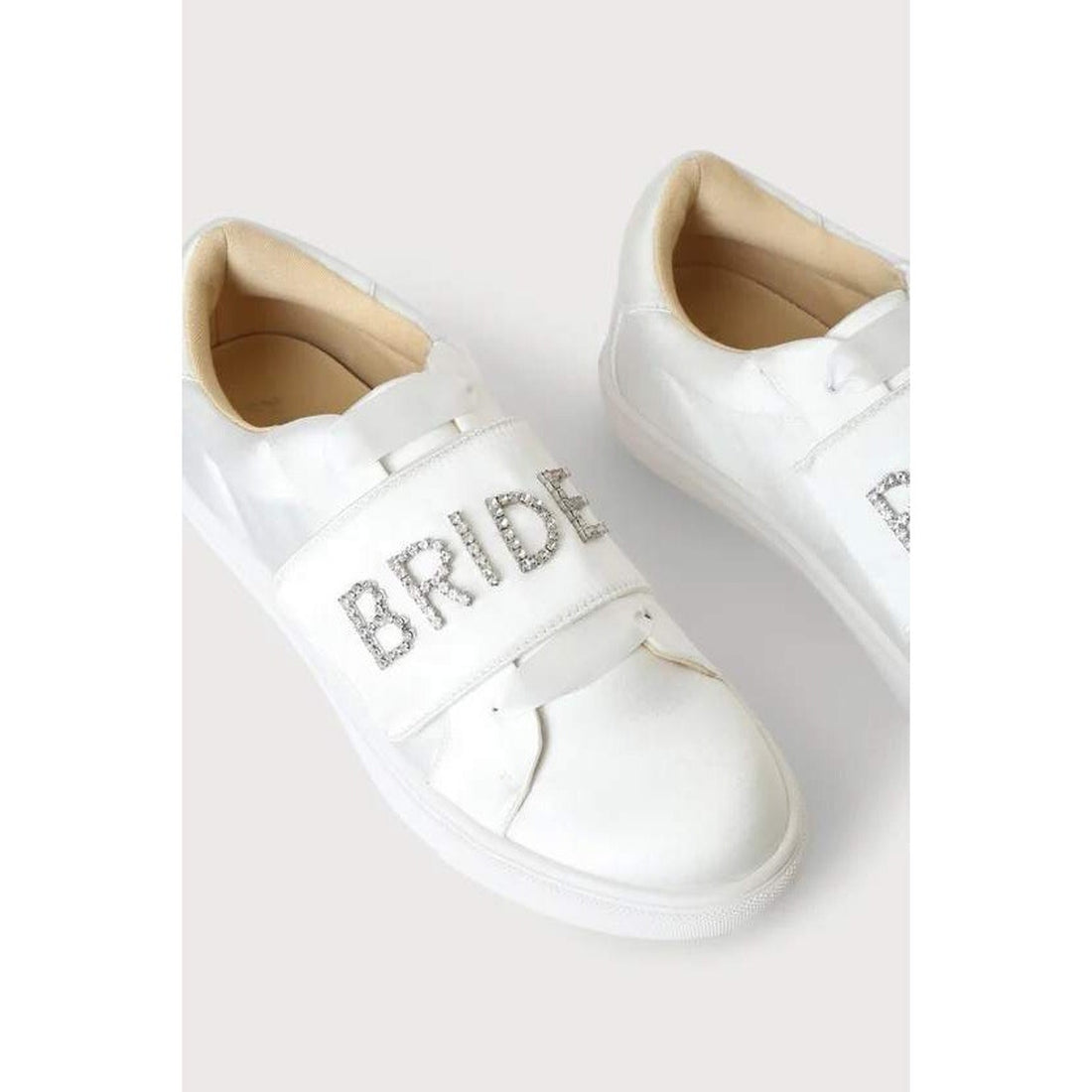 White sneakers with 'BRIDE' and 'BAND' text on a light gray background