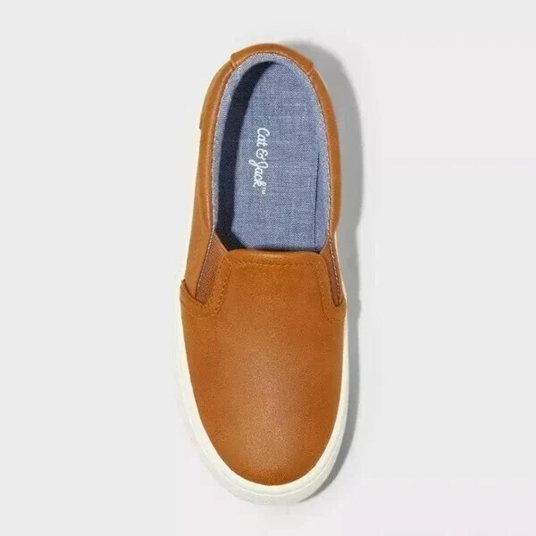 Brown slip-on shoe with white sole on a light gray background