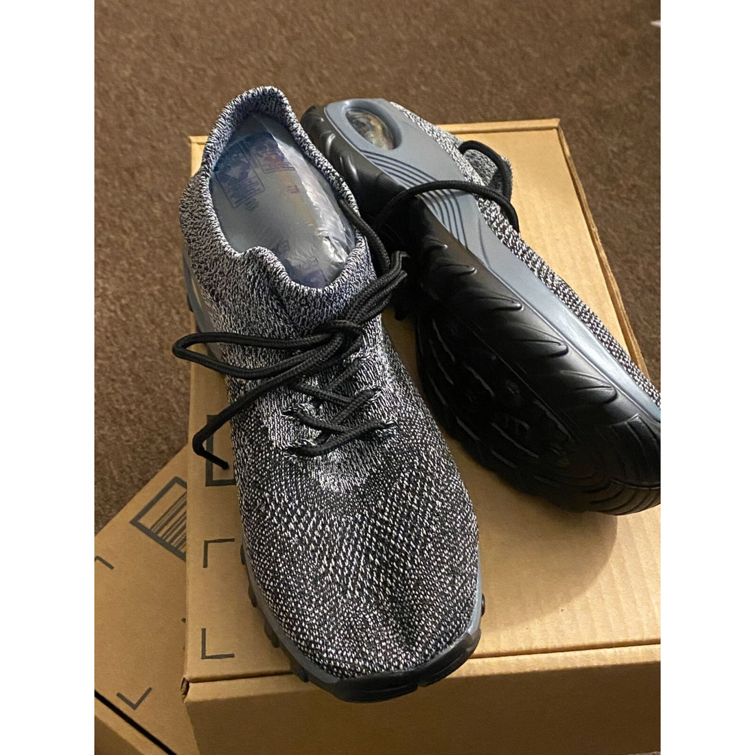 Gray athletic shoe with textured upper and black sole on a white background