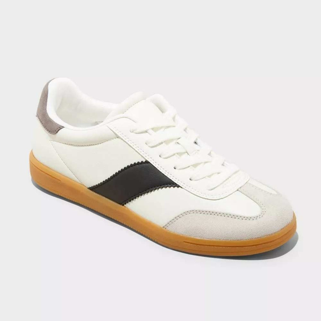 White sneaker with black accent and brown sole on a light gray background
