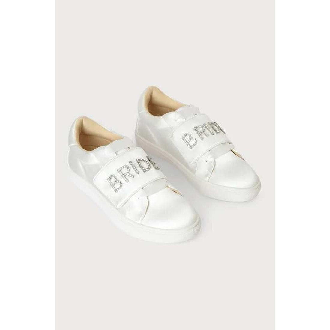 White sneakers with 'BRIDE' and 'BAND' text on a light gray background