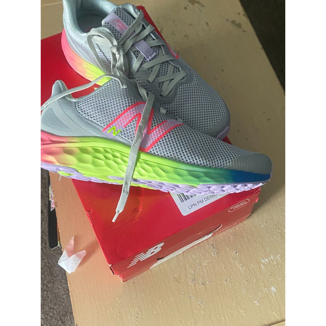 Gray athletic shoe with pink logo and colorful sole on a white background